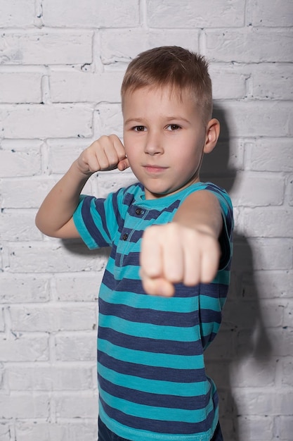 Handsome boy looks angry The child is offended threatens shows a fist Angry resentful aggressive child Portrait on white studio background Children's human emotions concept