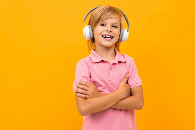 Handsome boy in pink t-shirt smiles and gesticulates isolated on orange background