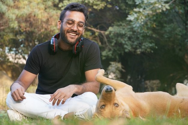 A handsome boy sitting in the park and playing with dogs