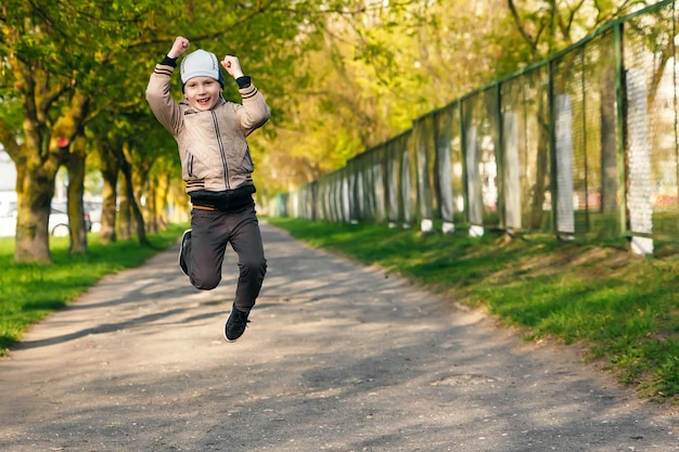 Bel ragazzo di sei anni giocando, saltando, correndo, sorridendo nel parco.