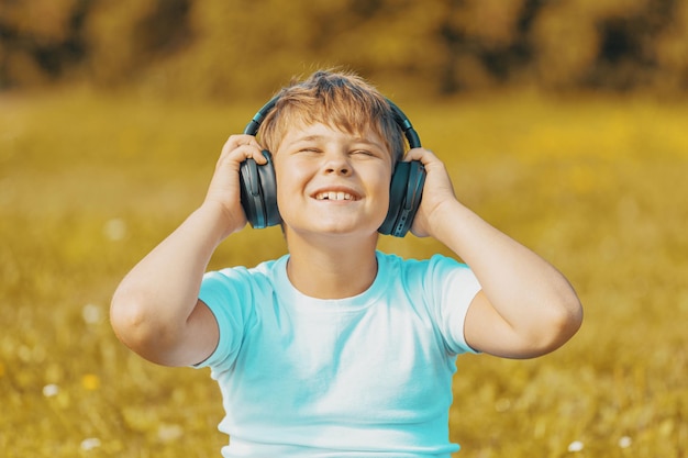 Handsome boy with headphones listening to music while sitting on the grass