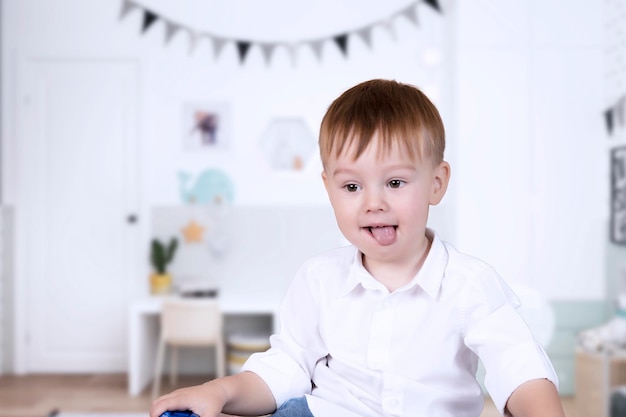 彼の顔にうれしそうな感情を持つハンサムな男の子が子供部屋で遊ぶ 子供たちとの教育ゲーム 子供の心理学