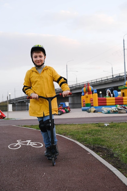 Foto un bel ragazzo con una giacca gialla e in protezione sta guidando uno scooter su una strada