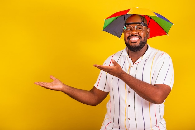 카니발 의상을 입은 잘생긴 브라질 아프리카 남자는 손과 손가락으로 측면 광고 카피 공간을 가리키는 전형적인 브라질 파티 카니발 향연 파티