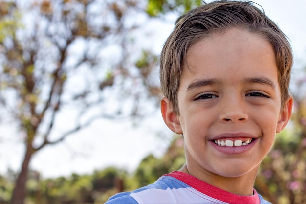 Handsome brazilian boy smiling with natural backdrop in blurred background