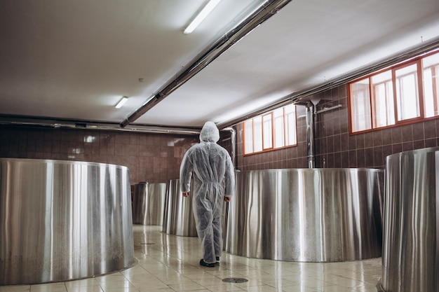 A handsome brewer examines beer from tanks in a brewery