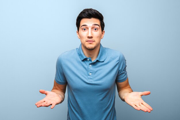 Handsome brunette man in blue polo shirt with serious face gesturing with his hands against. there is nothing to do