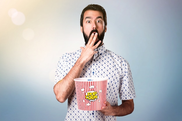 Handsome brunette man with beard eating popcorns