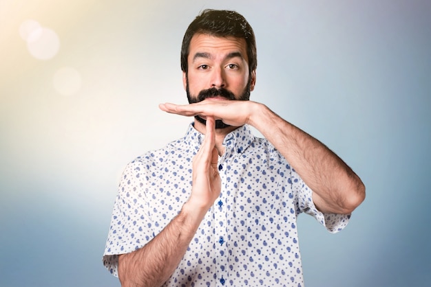 Handsome brunette man with beard making time out gesture