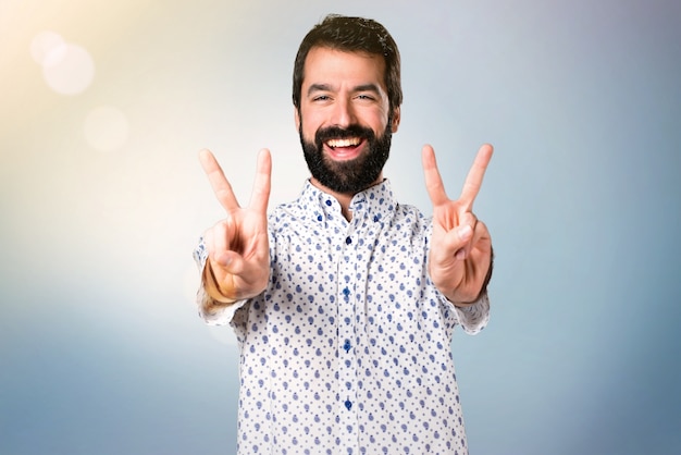 Handsome brunette man with beard making victory gesture