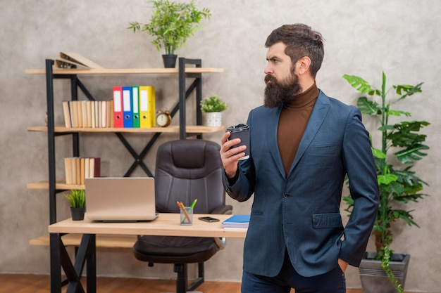 Handsome brutal ceo in businesslike suit hold morning coffee cup at the office guy