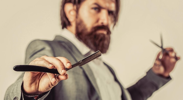 Foto un bell'uomo brutale barbiere con la barba e i baffi tiene il rasoio retro del barbiere