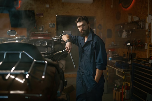 Foto bel riparatore brutale in abbigliamento da lavoro guardando il ritratto della fotocamera