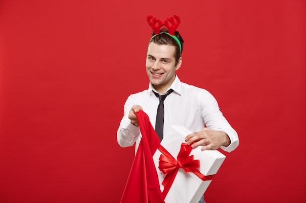 잘 생긴 사업가 메리 크리스마스를 축 하 하 고 새 해 복 많이 받으세요 순 록 머리 띠를 착용 하 고 산타 빨간 큰 가방을 들고.