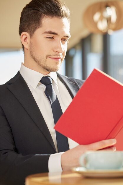 Handsome business man enjoying reading a book at the coffee shop