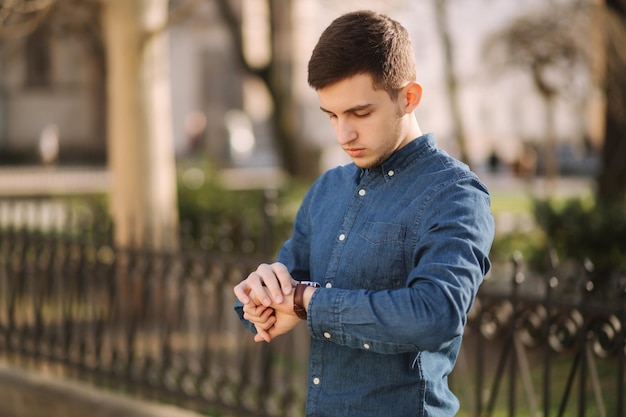 Handsome business man look at the watch in the city man ajust the exact time on the watch