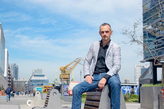 handsome business man posing sitting outdoors outside work buildings looking at camera