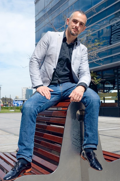 handsome business man posing sitting outdoors outside work buildings looking at camera