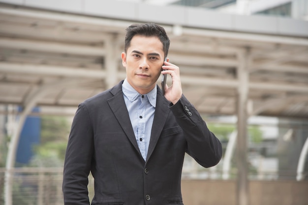 携帯電話で話すハンサムなビジネスマンアジア。