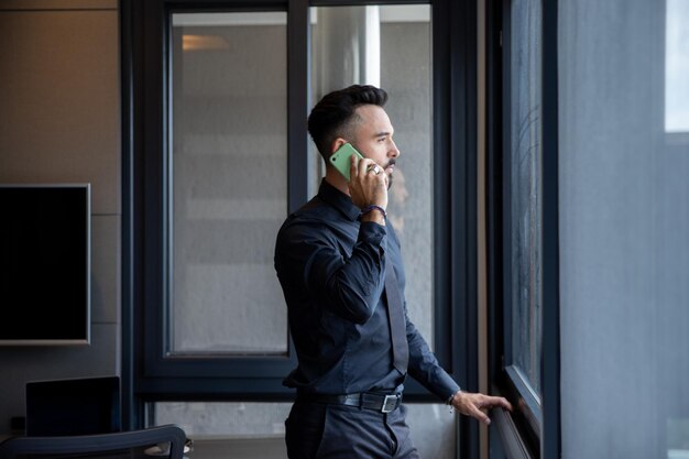 Handsome businessman in black suit talking on the phone in the office