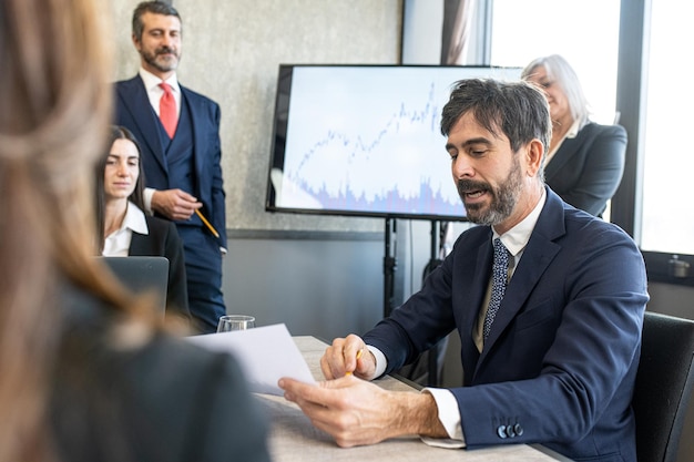 Handsome businessman explaining the trend of profits to the work team during birefing in the meeting room business people working in office