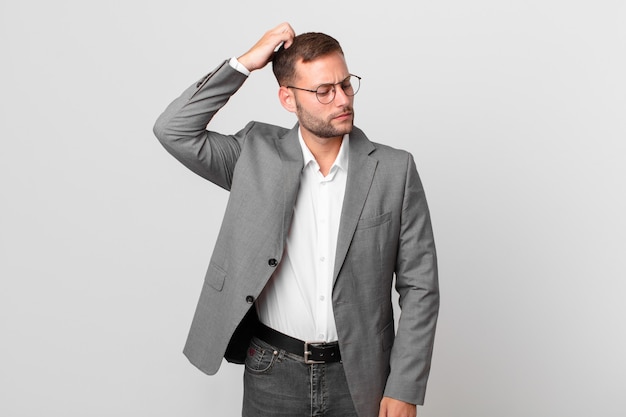 Handsome businessman feeling puzzled and confused, scratching head