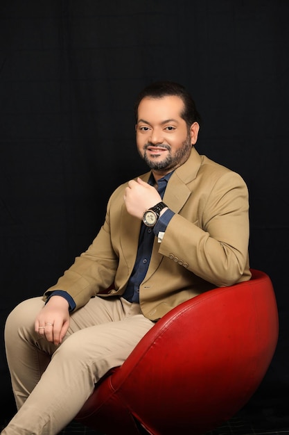 Handsome businessman in formal suit sit in red sofa