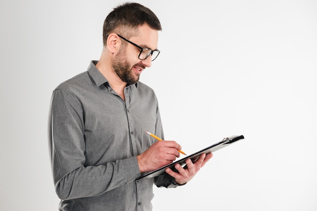 Handsome businessman holding clipboard writing notes.