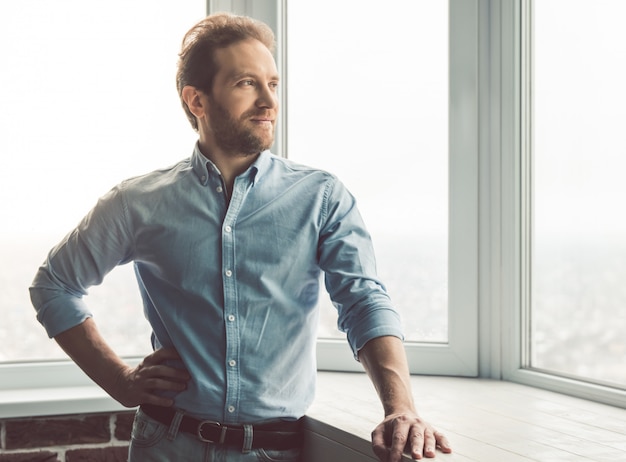 Handsome businessman is looking out the window.