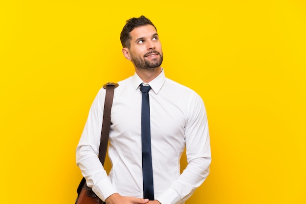 Handsome businessman over isolated yellow wall laughing and looking up