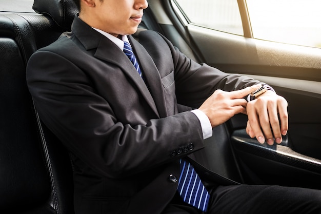 Photo handsome businessman looking on wrist watch in car
