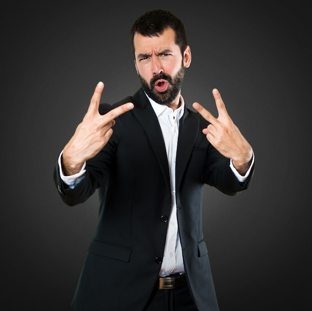 Photo handsome businessman making victory gesture on black background