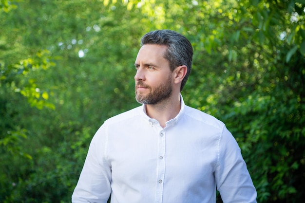 Handsome businessman man in white shirt looking aside natural background