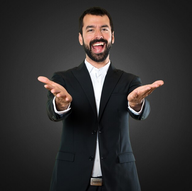 Handsome businessman presenting something on black background