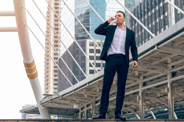 Handsome businessman relaxing and drinking water in the city.