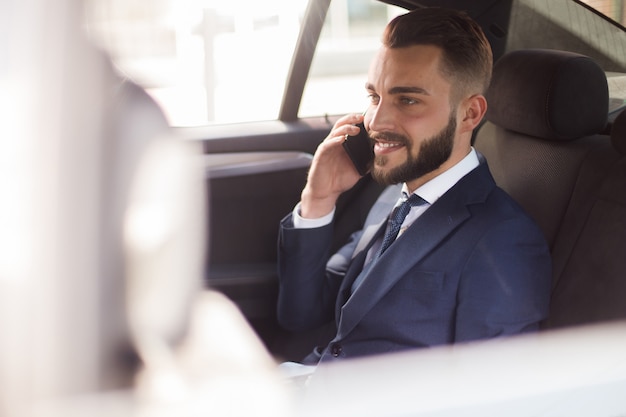 Handsome Businessman Speaking by Phone in Car