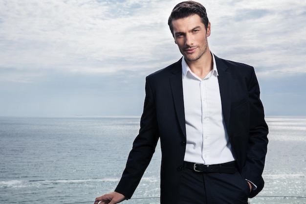 Photo handsome businessman standing outdoors with sea on wall