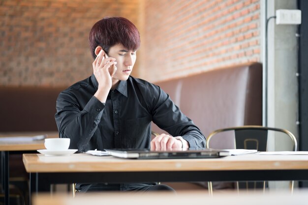 Handsome businessman in suitspeaking on the phone in coffee shop