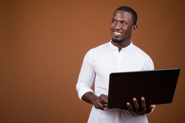 Handsome businessman using laptop computer against brown