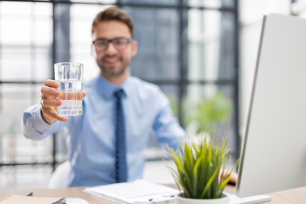 Handsome businessman using PC and drinking water in office area