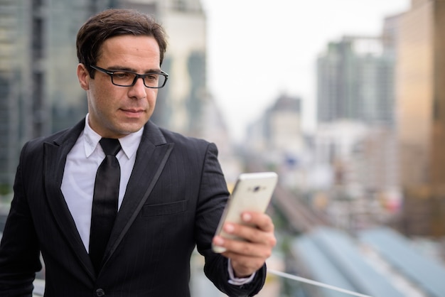 Handsome businessman using phone in the city