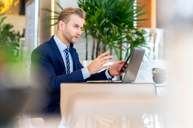 handsome businessman using smart phone and laptop while working in office