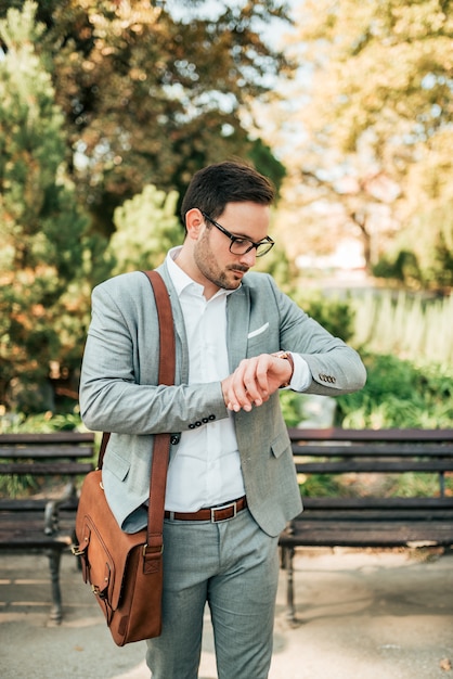 Handsome businessman walking and checking the time on his wristwatch.