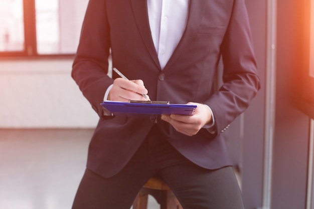 Handsome businessman wearing a black suit with a clipboard