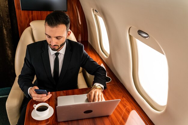 Handsome businessman wearing elegant suit  flying on exclusive private jet