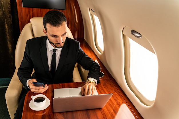 Красивый бизнесмен в элегантном костюме летит на эксклюзивном частном самолете