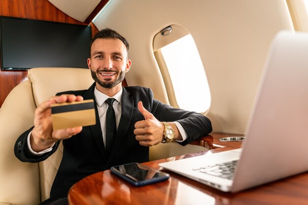 Uomo d'affari bello che porta vestito elegante che vola su un jet privato esclusivo