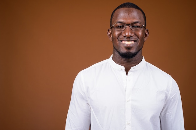 Handsome businessman wearing eyeglasses against brown