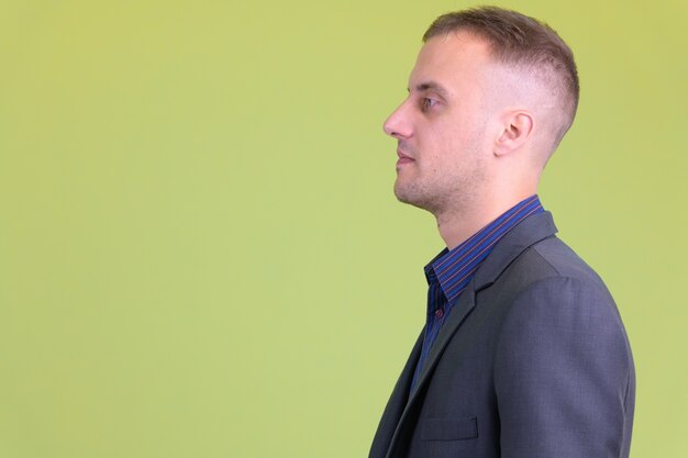 Photo handsome businessman wearing suit against colored wall