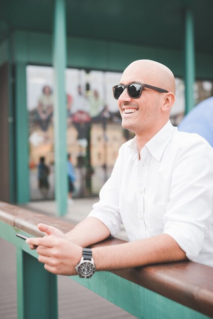 handsome businessman wearing sunglasses, leaning on a handrail 